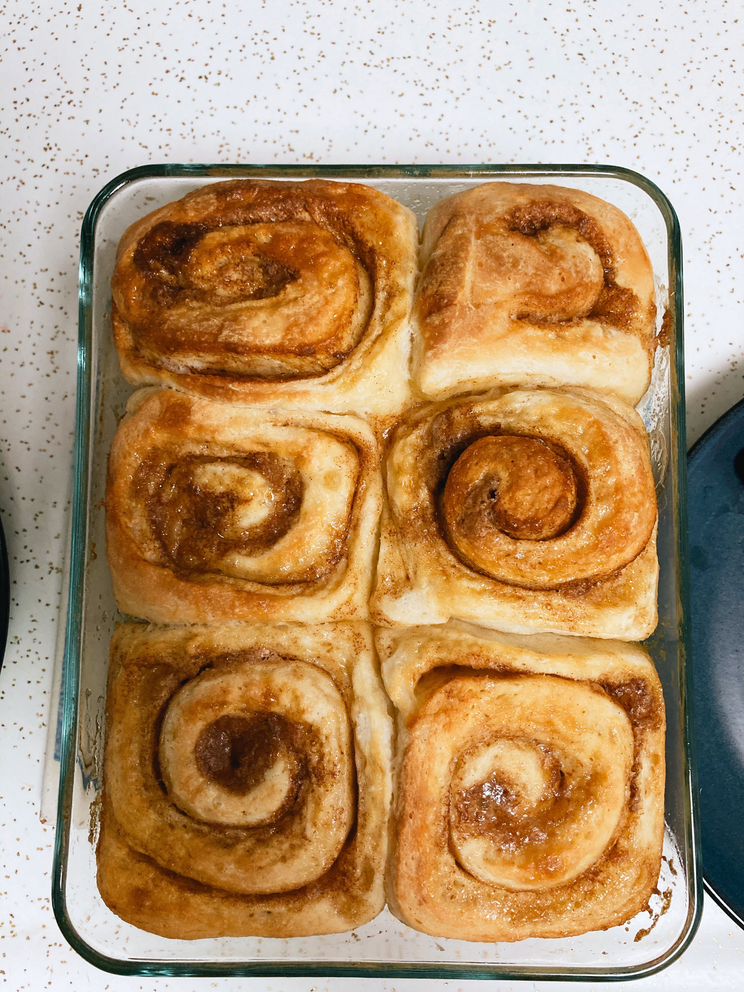 A bunch of baked cinnamon rolls in a baking tray.